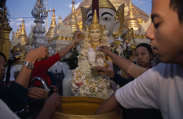 MYANMAR, Yangon People making offerings of flowers and water at shrine in Shwedagon