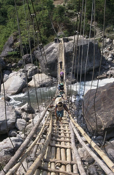 NEPAL, Annapurna Circuit Trek Crossing a sagging suspension bridge over the Khudi
