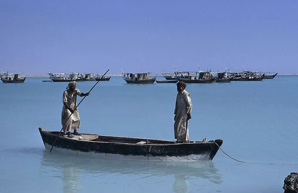 QATAR, Khor Fishermen in a wooden canoe with fishing boats at anchor beyond
