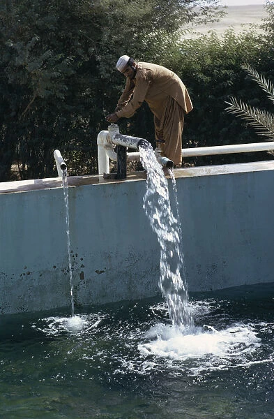 QATAR Man letting water into irrigation pool on a farm