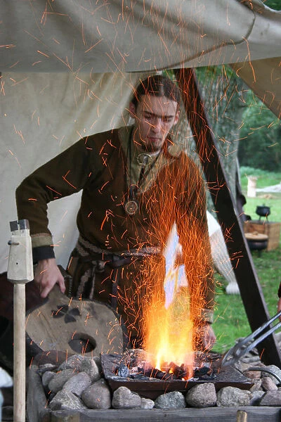 A Saxon using bellows to light a fire