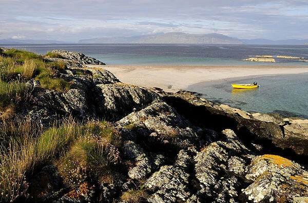 SCOTLAND, Argyll, Isle Of Iona, Rocks & sandy beach with views of Mull & yellow boat