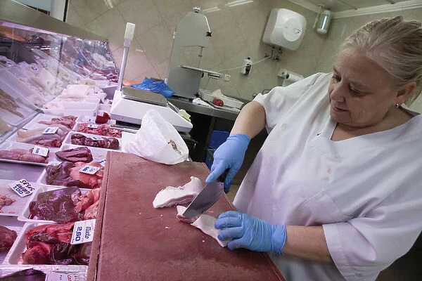 Spain, Castilla La Mancha, Toldeo, Butcher preparing meat for display