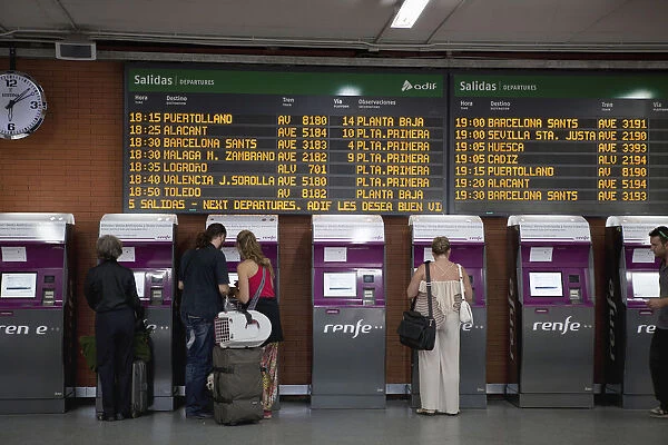 Spain, Madrid, Passengers using the self-service ticket machines in front of the