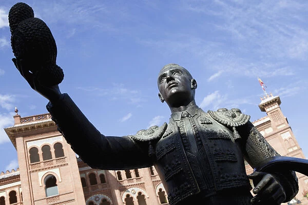 Spain, Madrid, Statue of a matador with the Plaza de Toros de las Ventas in the