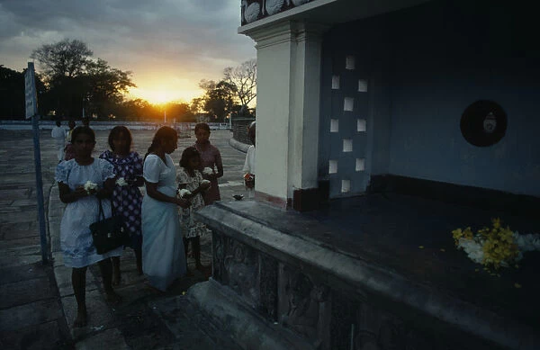 Sri Lanka, Anuradhapura, Wesak Festival, Women with flower offerings at sunset