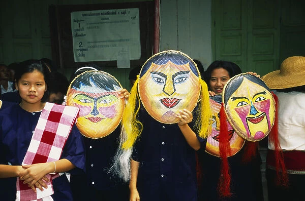 Thailand, Sukhothai, Si Satchanalai, Girls wearing large painted masks to celebrate novice monks
