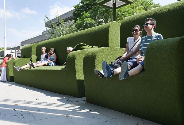 Tourists relax in giant green sofas on the South Bank of the river Thames, London England