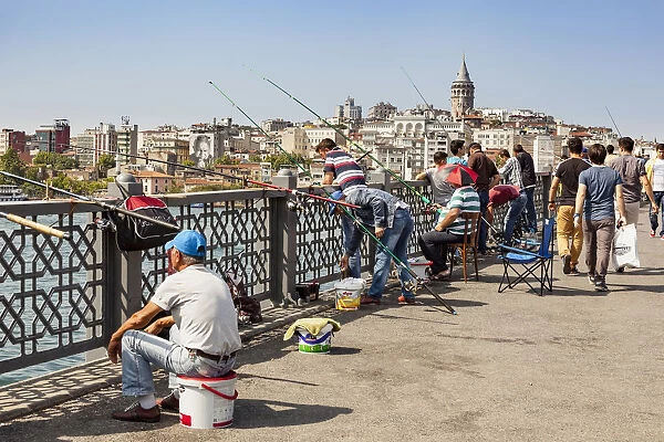 Turkey, Istanbul, Men fishing on Galata Bridge, Galata Tower in background