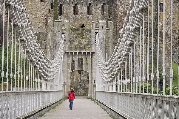 Wales, Conwy, Conwy Suspension Bridge with figure walking towards the walls of Conwy Castle