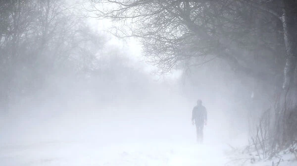 A man walks along the A53 Buxton Road which is closed due to heavy snow fall, near Leek