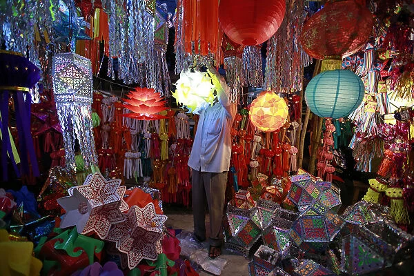 A vendor hangs a lantern for sale at a Diwali market in Mumbai