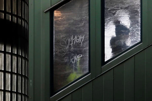 A woman is seen in silhouette through an ice covered window of a subway staircase in