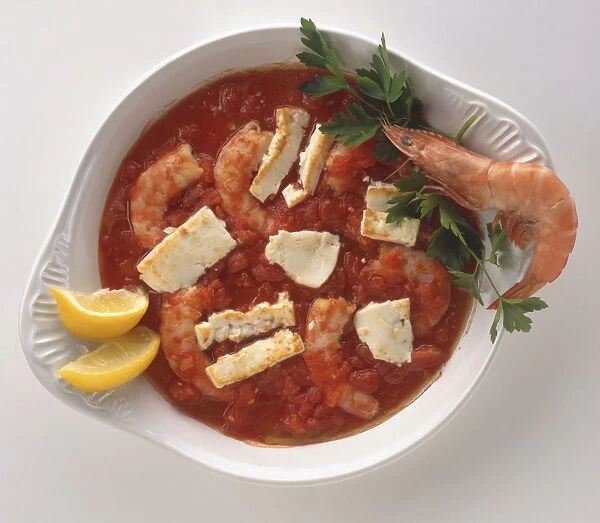 Overhead view of Garides giouvetsi, a modern dish of large shrimps or prawns baked in a tomato, olive oil and parsley sauce and topped with feta cheese, served in a white dish