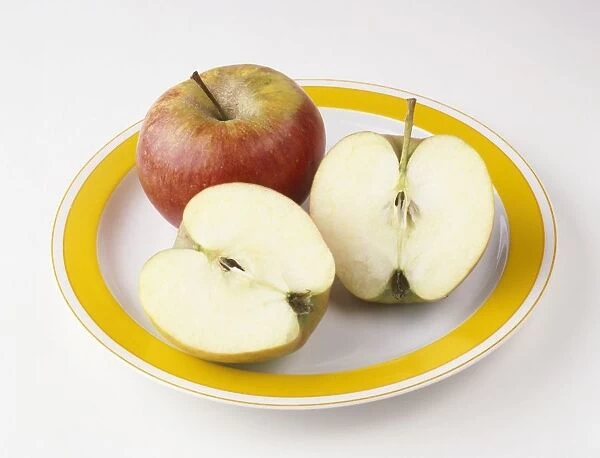 Whole and sliced red apple on plate