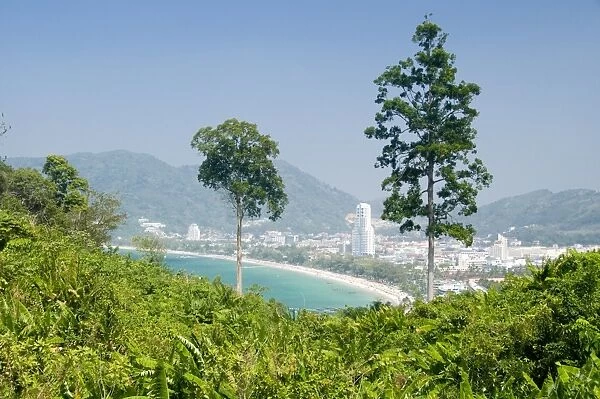 Thailand, Phuket, Ao Patong, tourist resort seen from lush hill with mountains in distance