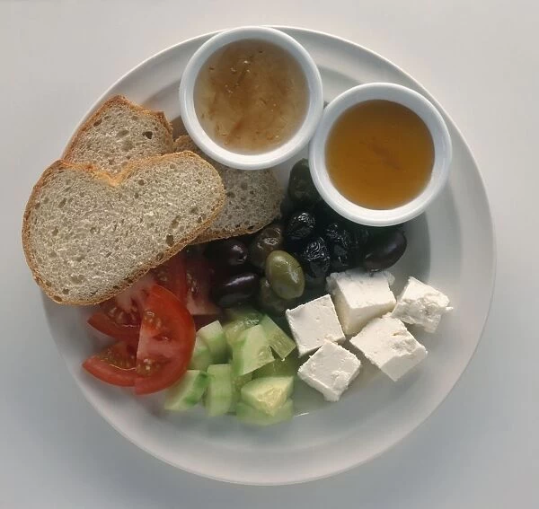 Turkish breakfast consisting of feta-type cheese, cucumber, tomato, olives, bread, honey and jam, on a plate, view from above