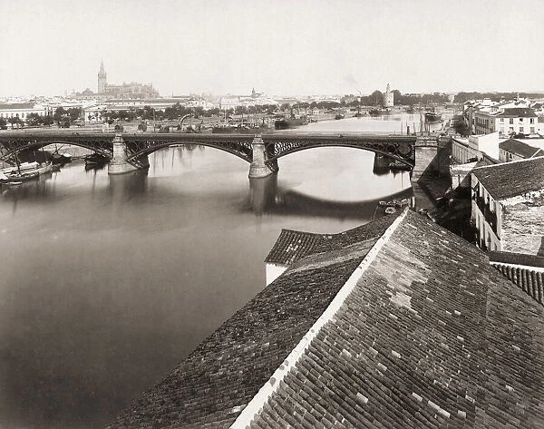 Seville, Seville Province, Andalusia, Spain circa 1880. The Guadalquivir River. In the mid-distance is the Triana Bridge. The Cathedral with the Giralda Tower can be seen in the background, left, and the Torre de Oro, or Tower of Gold, to the right. From a 19th century photograph