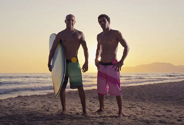 Two young men standing on the beach with a surfboard; Tarifa cadiz andalusia spain