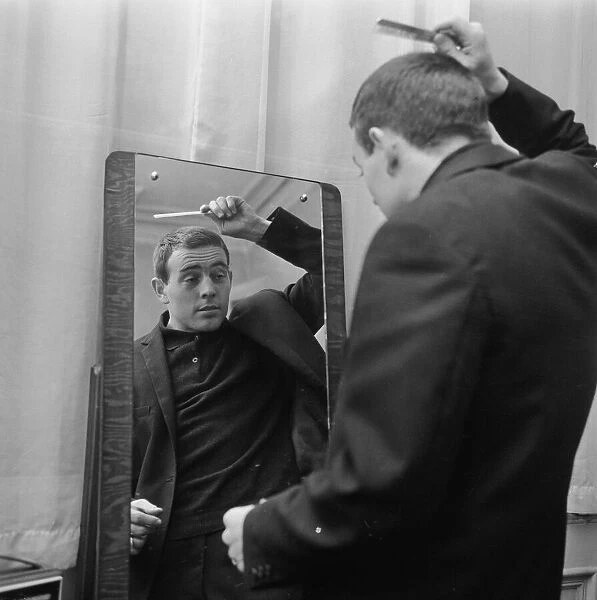 Liverpool player Ian St John looks in the mirror to comb his hair as he gets ready for