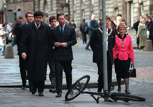 Prince Charles walking in the High Street Edinburgh about to pass bicycle on ground