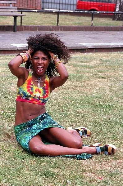 SINITTA SITTING IN PARK WITH HER HANDS IN HER HAIR IN PROMOTIONAL HAIR PHOTOCALL