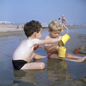 Two boys playing in a pool on a sandy beach