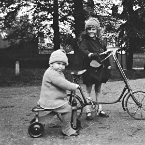 Girl and toddler riding a bicycle and a tricycle