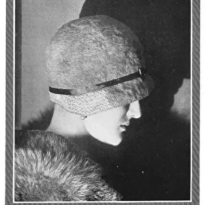 Model wearing a fur and a deep cloche hat, crocheted in Velveno and brushed to make it fluffy. Date: 1930