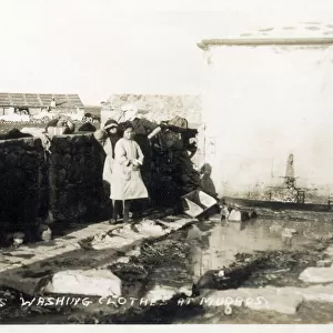 Moudros, Lemnos, Greece - Laundry in the open air - washing clothes by rubbing the garments against large stones and then drying over walls and on fences in the hot sun. Date: 1922