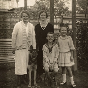 Four people with a German Shepherd dog in a garden