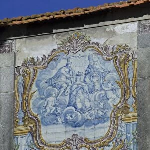 A beautiful blue and white tiled azuleju tableau with elaborate gold tiled frame preserved in an old wall in the City of Oporto, Portugal, Europe