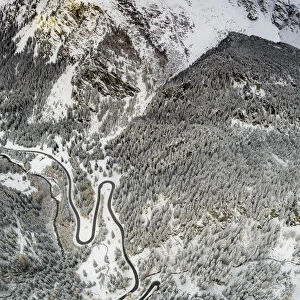 Bends of Maloja Pass road on snowy mountain ridge, aerial view, Bregaglia Valley