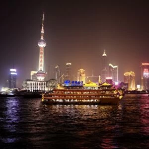 Boat set against Shanghai illuminated skyline, Shanghai, China, Asia