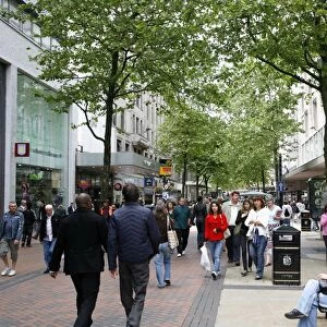 People walking down New Street, a pedestrian street with many shops. Birmingham