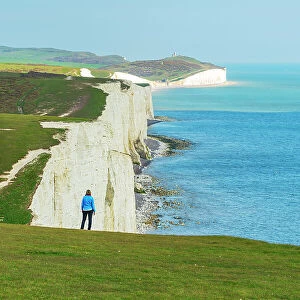 Rear view of woman admiring the view of the coast along the Seven Sisters chalk cliffs, South Downs National Park, East Sussex, England, United Kingdom, Europe
