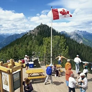 Tourists beneath the Canadian flag on Sulphur Mountain in the Banff National Park in Alberta