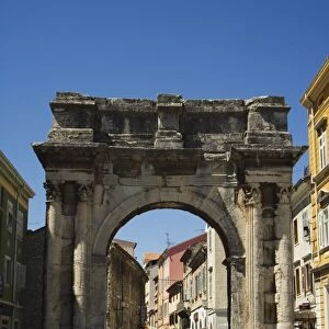 Tourists walking through stone arch in Old Town, Pula, Istria Coast, Croatia, Europe