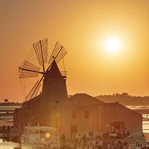 Marsala, Sicily. Tourists visiting the Marsala saltern at sunset with the windmill