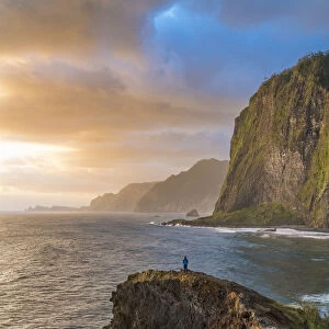 Person on a cliff watching the sunrise. Faial, Santana municipality, Madeira Island