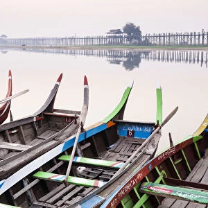 Traditional Burmese boats at sunrise on Taungthaman Lake with U Bein Bridge in the