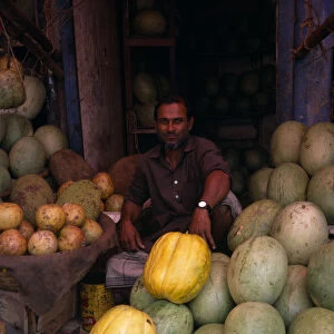 BANGLADESH, Dhaka Man selling durians and melons in fruit market