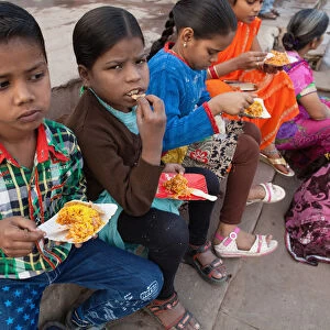 India, Uttar Pradesh, Varanasi, Children eat a snack of bhel puri on the ghats