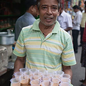 India, West Bengal, Kolkata, Chai vendor with a tray of tea in plastic cups in Sudder Street