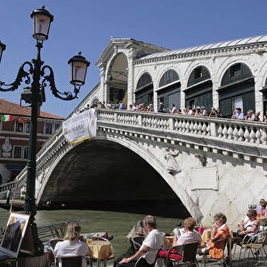 Italy, Veneto, Venice, Rialto bridge over the Grand Canal with cafe in foreground