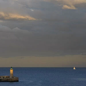 A lighthouse is seen at dusk in a harbour in Valletta
