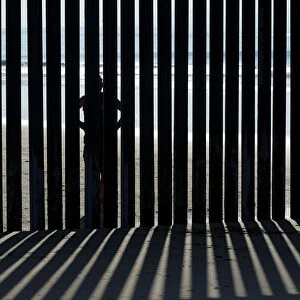 A person looks through the border wall towards the United States at Border Field State