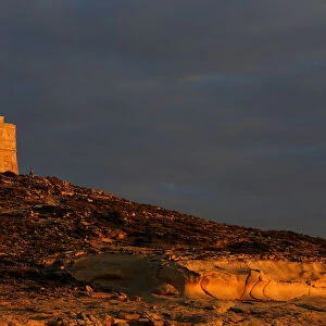 Tourists walk near Dwejra Tower, a watchtower built in 1652