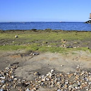 Exposed rocky outcrop on beach at low tide, with lifeboat boathouse, Bembridge Lifeboat Station, Bembridge