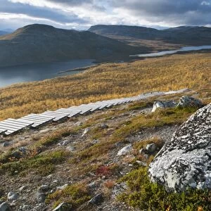 Rock and wooden steps leading to summit of fell, Malla Strict Nature Reserve and Lake Kilpisjarvi in background